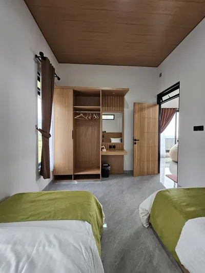 Kamar tidur dua single bed dengan lemari pakaian kayu.